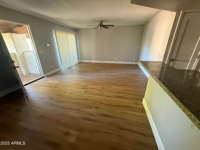 a view of empty room with wooden floor and fan