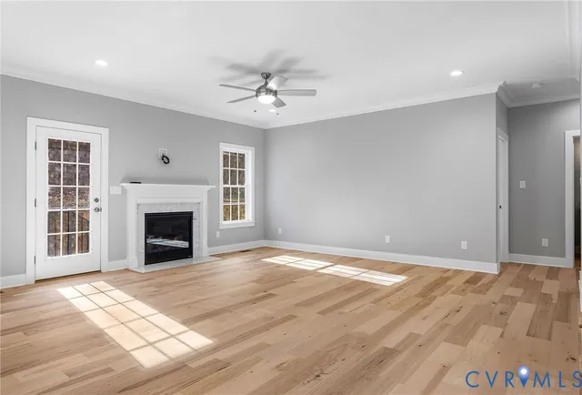 a view of an empty room with wooden floor fireplace and a window