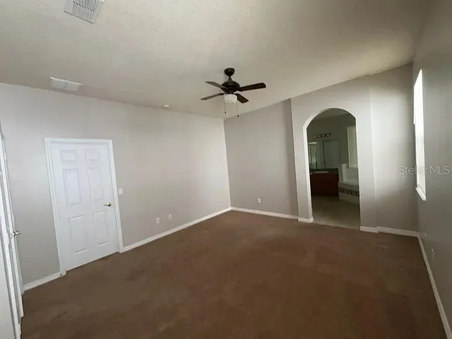 an empty room with a ceiling fan and a window