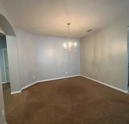 a view of an empty room with a chandelier fan