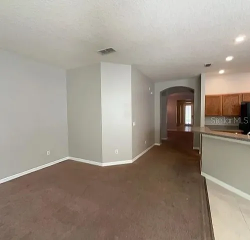 a view of empty room with kitchen