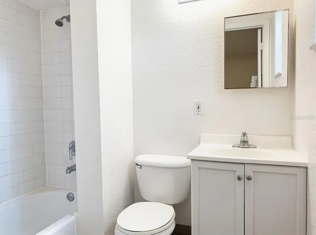 a view of an empty room with kitchen and a window