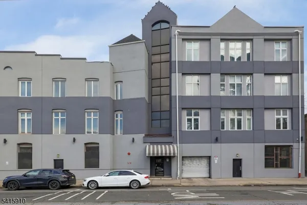 a front view of a building with lot of cars and trees
