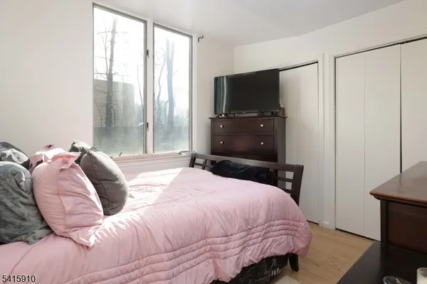 a bedroom with a bed a tv and wooden floor