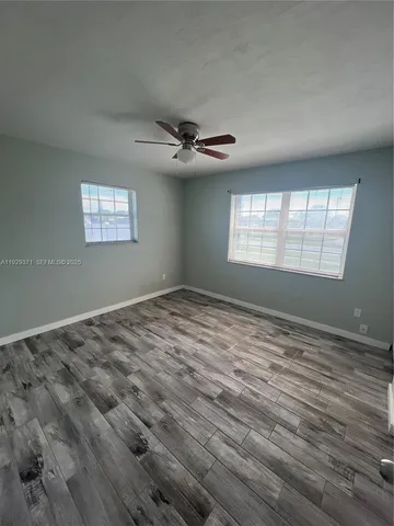 a view of empty room with wooden floor and fan