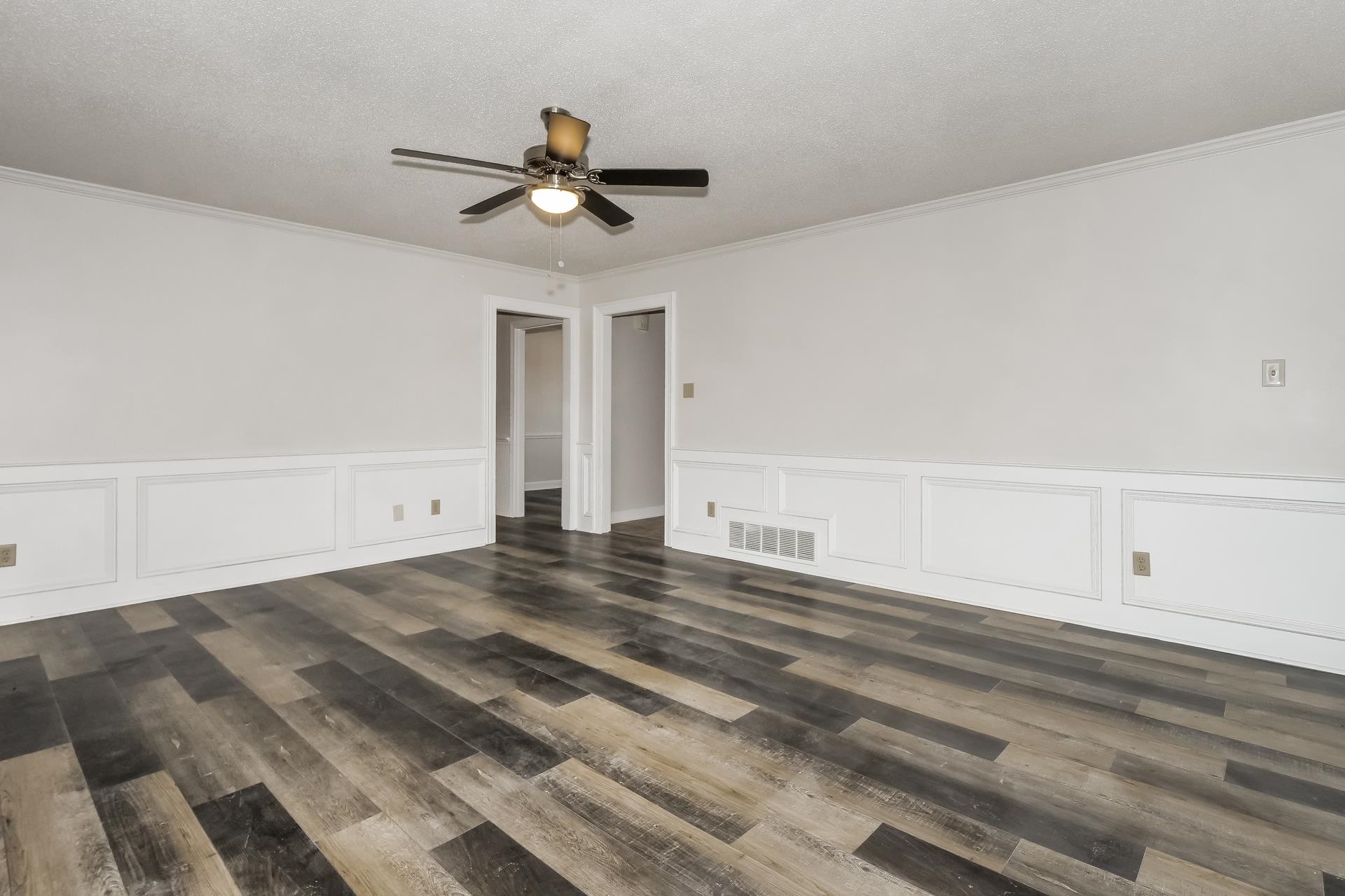 675 South Collierville Arlington Road Collierville, TN 38017 - Photo 3 of 17 Unfurnished room featuring dark wood-style flooring, a wainscoted wall, a ceiling fan, a decorative wall, and crown molding