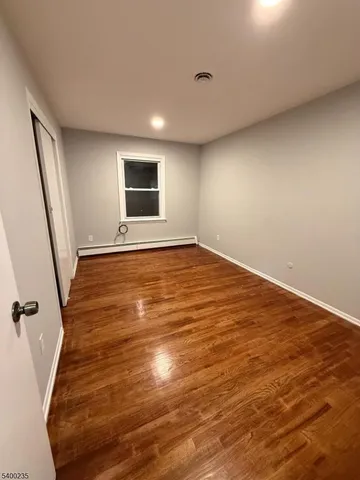 an empty room with wooden floor and window