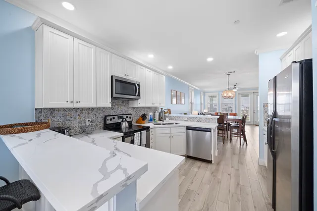 a kitchen with a refrigerator a stove top oven a sink dishwasher a dining table and chairs with wooden floor