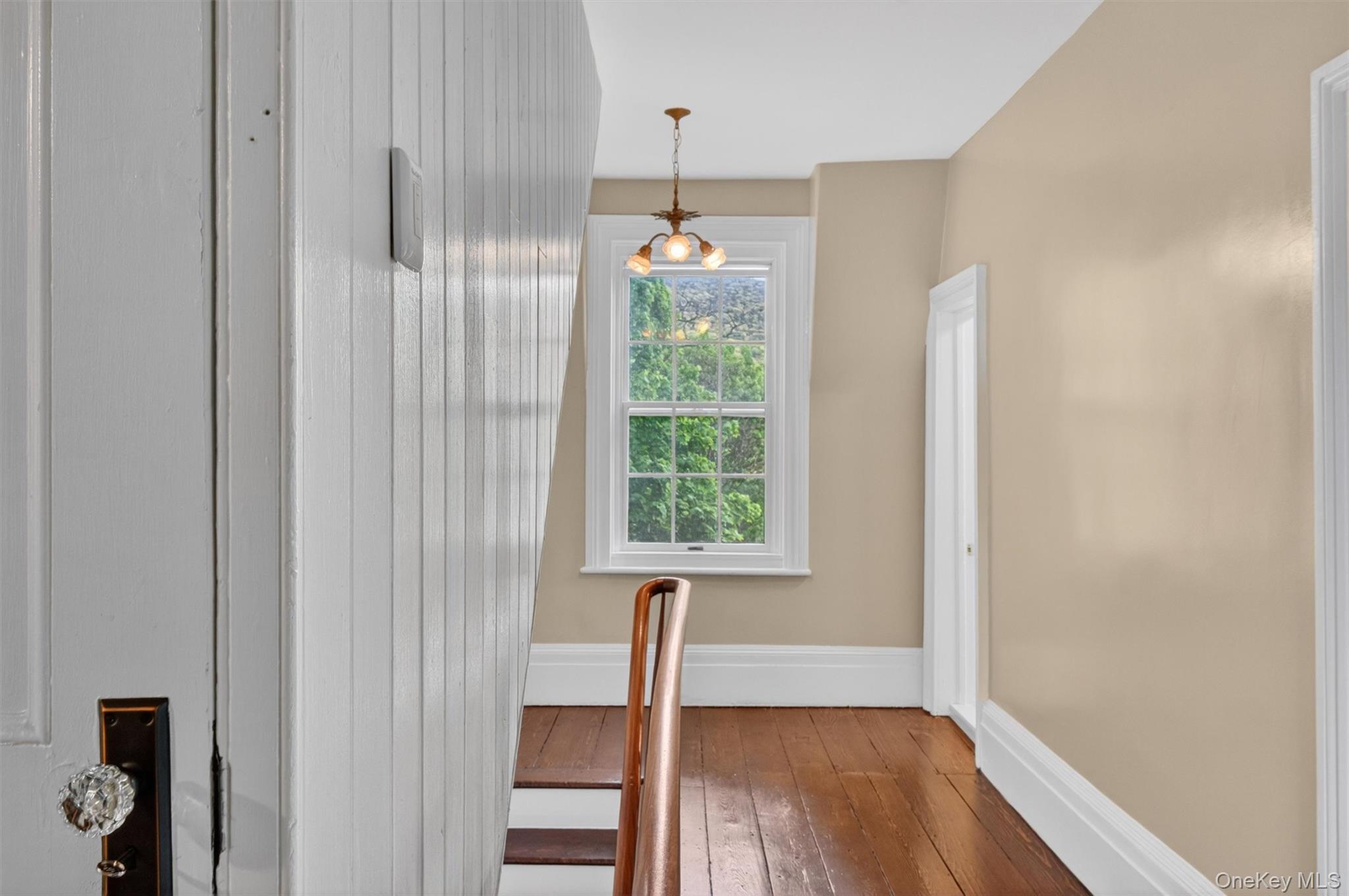 121 Old Glenham Road Fishkill, NY 12524 - Photo 33 of 50 Second-story hallway featuring rich hardwood flooring, antique lighting fixture, a classic wooden balustrade, and doors leading to other living areas.