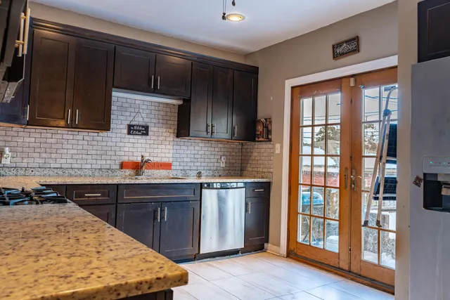 a kitchen with stainless steel appliances granite countertop wooden cabinets a stove top oven a sink and dishwasher