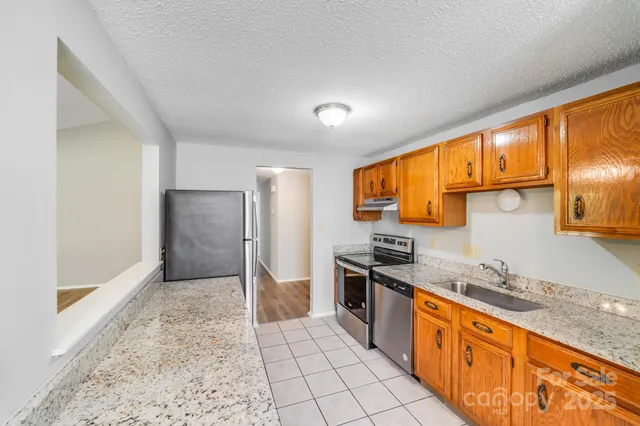 a large kitchen with stainless steel appliances granite countertop a refrigerator and a sink