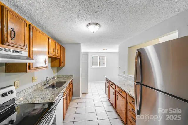 a kitchen with stainless steel appliances granite countertop a refrigerator a stove a sink and a microwave