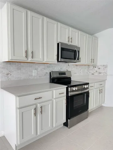 a kitchen with white cabinets and stainless steel appliances