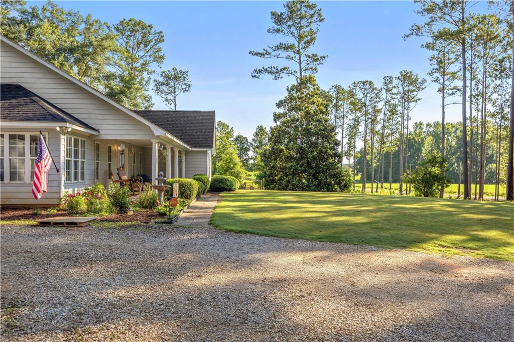 62 McCarthy Road Opelika, AL 36804 - Photo 27 of 74 Gravel driveway leading to a residence with light-colored siding and a covered front porch