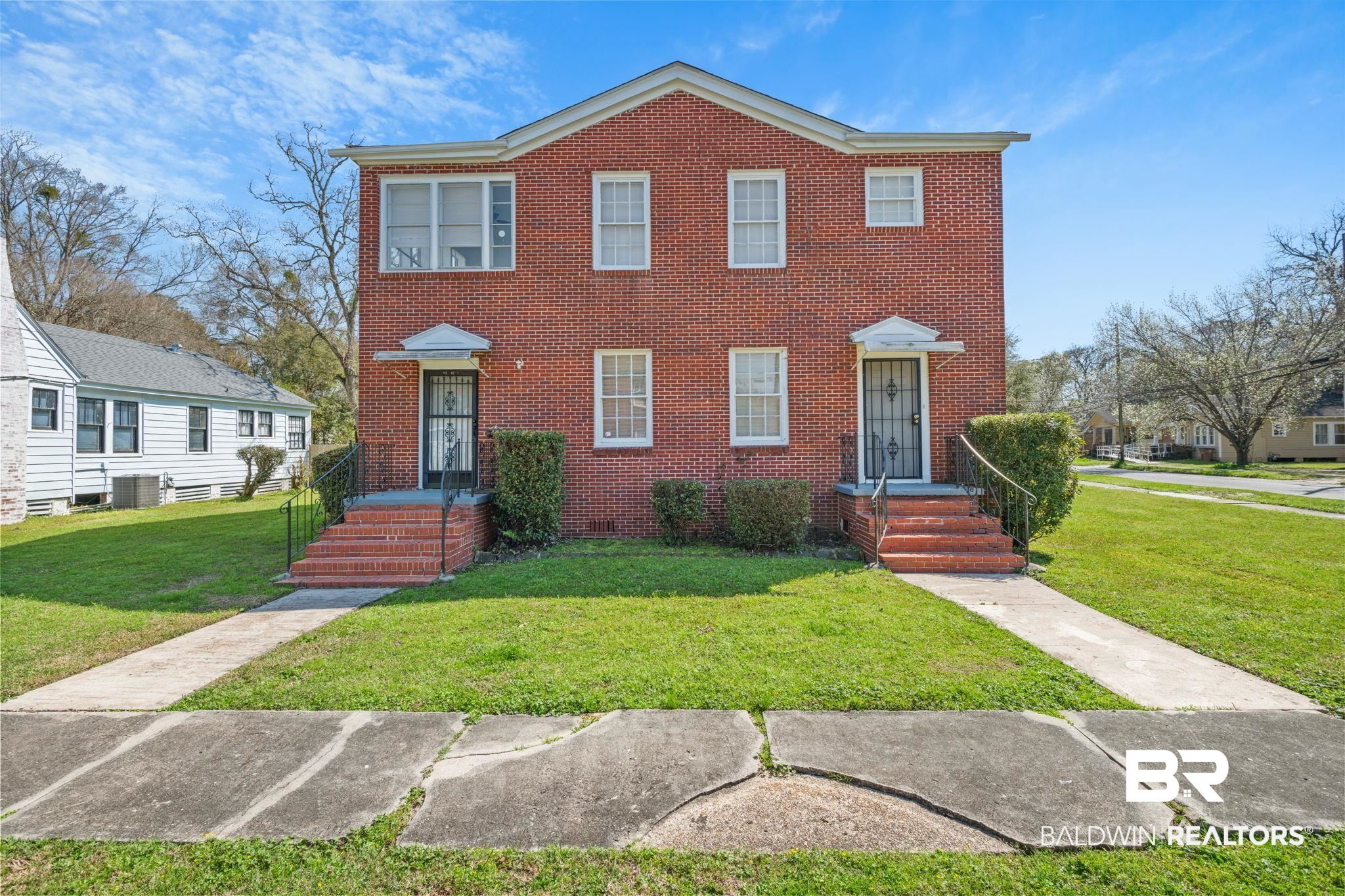 View of front of home featuring a front yard, central AC unit, and brick siding