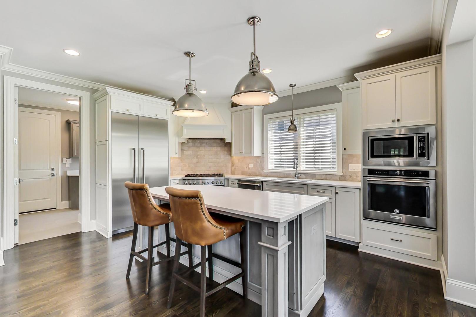 8310 Waterview Drive Burr Ridge, IL 60527 - Photo 7 of 35 a kitchen with stainless steel appliances a stove a sink a kitchen island with a dining table and chairs