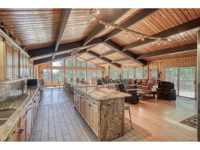 a open kitchen with stainless steel appliances granite countertop a wooden floors and a large window