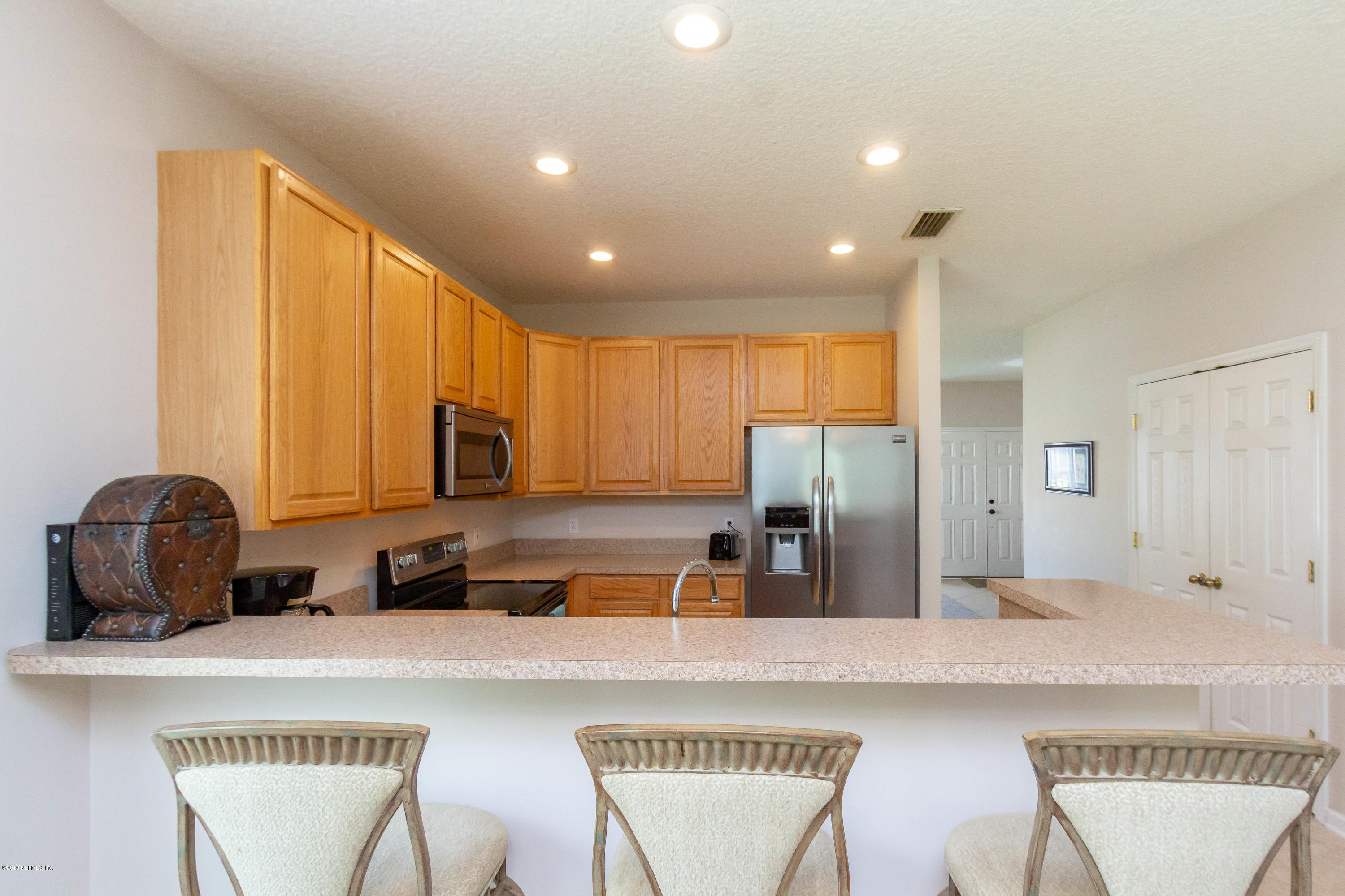 321 Stonehurst Parkway St. Augustine, FL 32092 - Photo 15 of 60 a kitchen with stainless steel appliances granite countertop a stove a sink a refrigerator white wooden cabinets with two chairs and a refrigerator