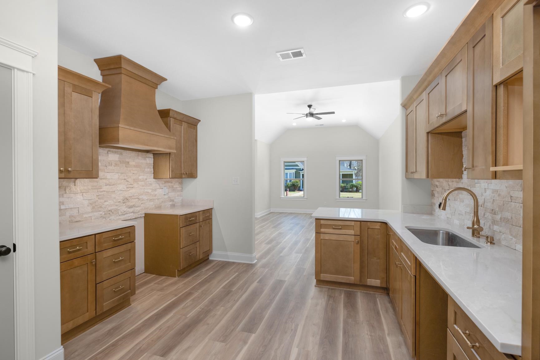 319 North Maple Street Covington, TN 38019 - Photo 16 of 32 Kitchen with decorative backsplash, light stone counters, light wood-type flooring, recessed lighting, and wood finish cabinets