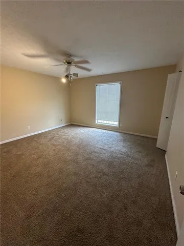 an empty room with a ceiling fan and a window