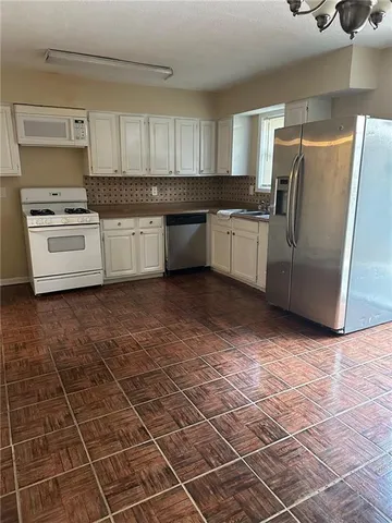 a kitchen with granite countertop a stove a sink and a refrigerator