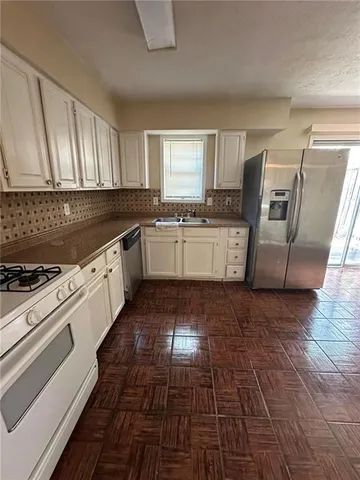 a large kitchen with granite countertop a stove a sink dishwasher and a refrigerator