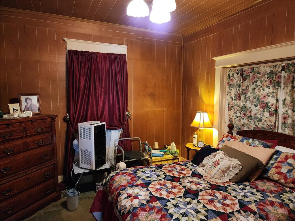 403 Barker Street Cumby, TX 75433 - Photo 8 of 16 Wood-paneled walls and ceiling with white trim, featuring two windows with valances