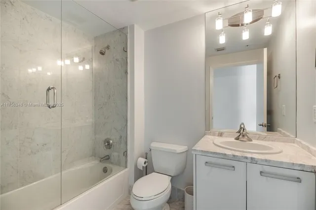 a bathroom with a granite countertop sink a toilet and shower