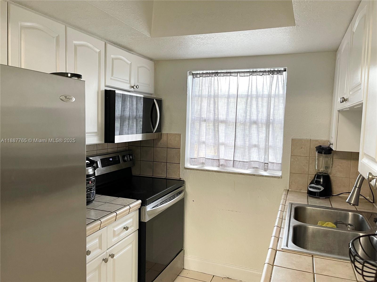 9301 Southwest 4th Street, Unit 224C Miami, FL 33174 - Photo 6 of 19 a kitchen with a sink appliances and cabinets