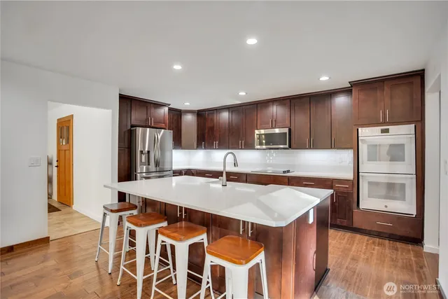 a kitchen with stainless steel appliances granite countertop a table chairs sink refrigerator and microwave