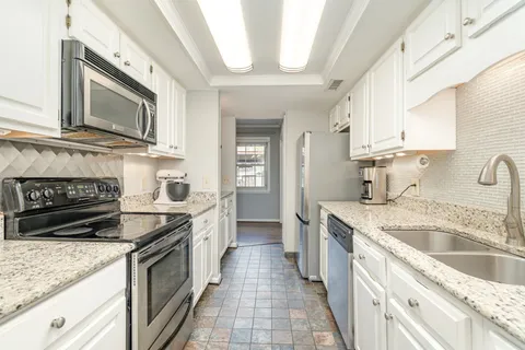 a kitchen with stainless steel appliances granite countertop a sink stove and cabinets