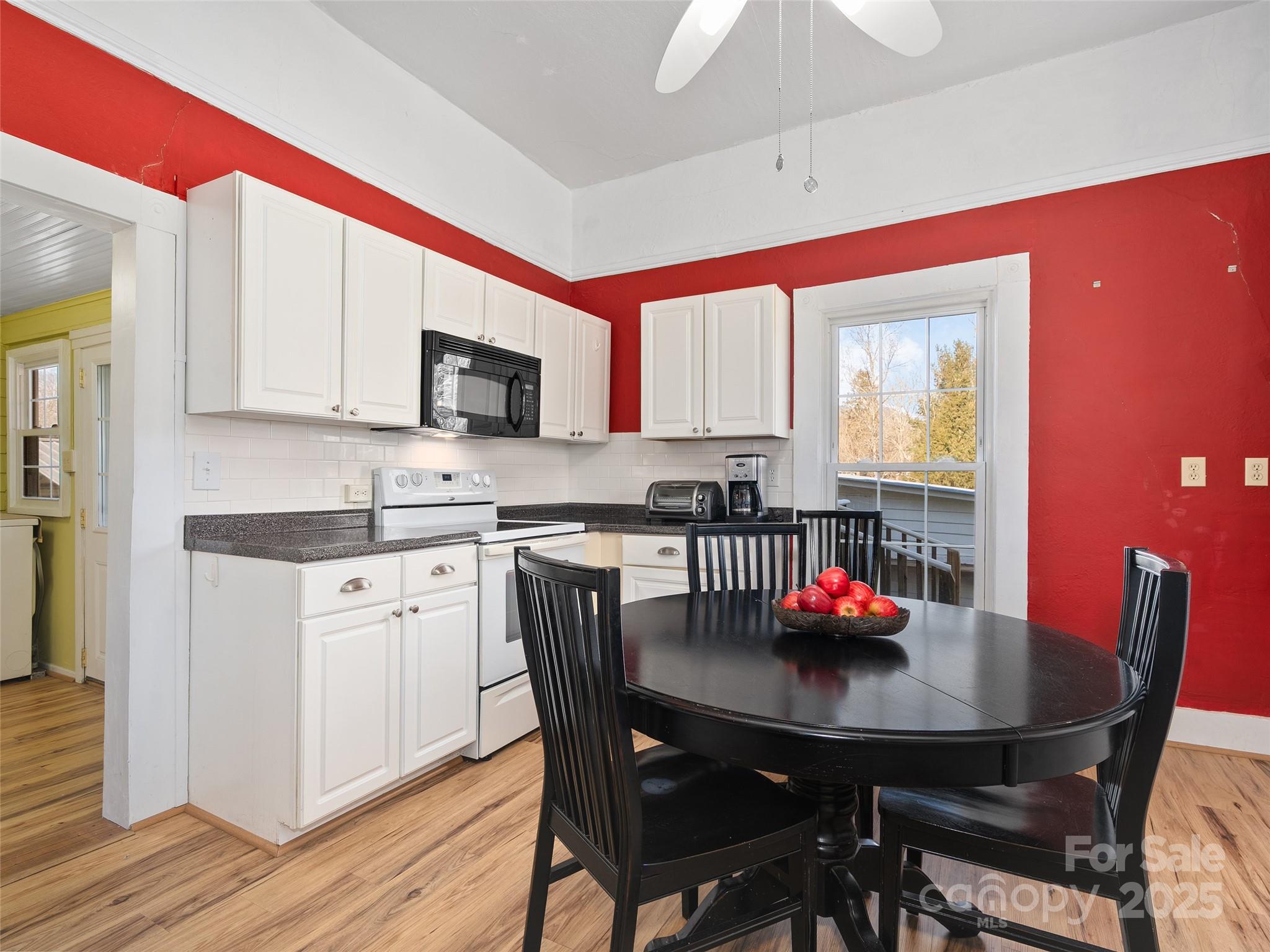 4739 Old Clyde Road Clyde, NC 28721 - Photo 8 of 35 a kitchen with granite countertop a dining table chairs and white cabinets