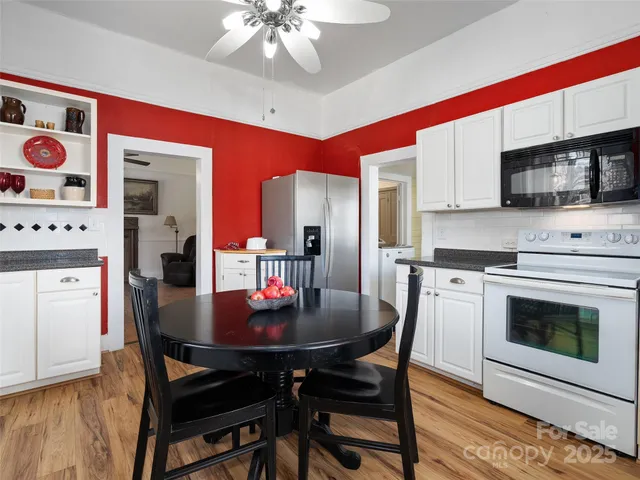 a kitchen with stainless steel appliances granite countertop a stove a microwave a dining table and chairs with wooden floor