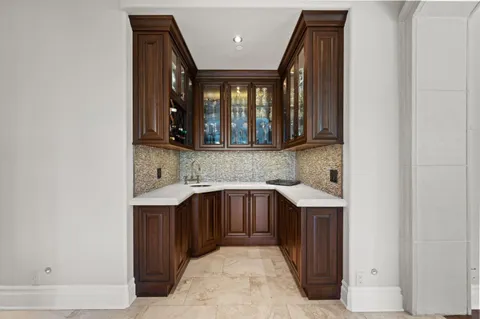 a view of a white house with a large pool and table and chairs under an umbrella