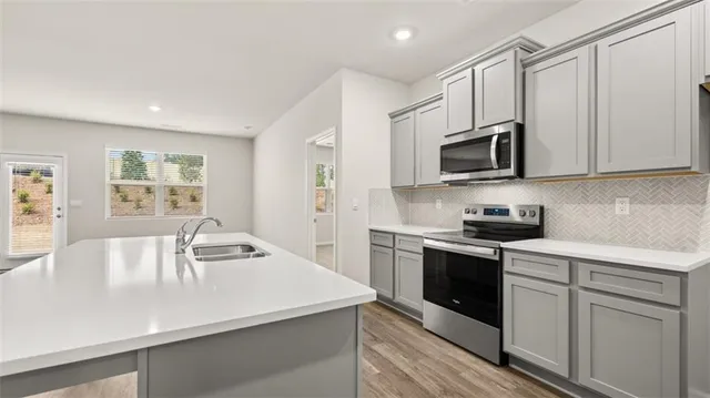 a kitchen with stainless steel appliances a stove microwave sink and refrigerator