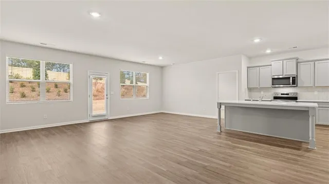 a view of an empty room with a window and wooden floor