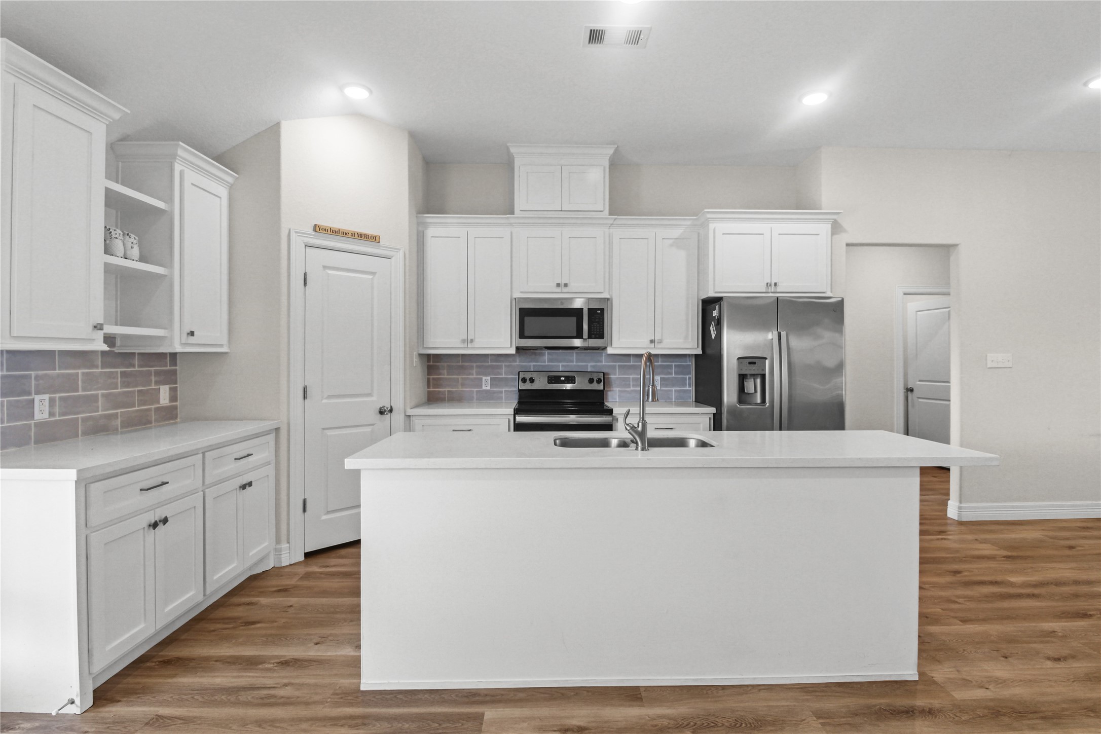 1208 East Henderson Road Angleton, TX 77515 - Photo 10 of 29 a kitchen with stainless steel appliances a refrigerator a stove top oven a sink and white cabinets