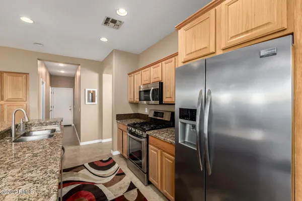 a kitchen with stainless steel appliances granite countertop a refrigerator a stove and a sink with wooden floor