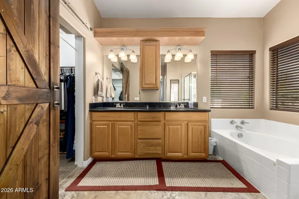 a bathroom with a tub a sink and a large mirror next to a window