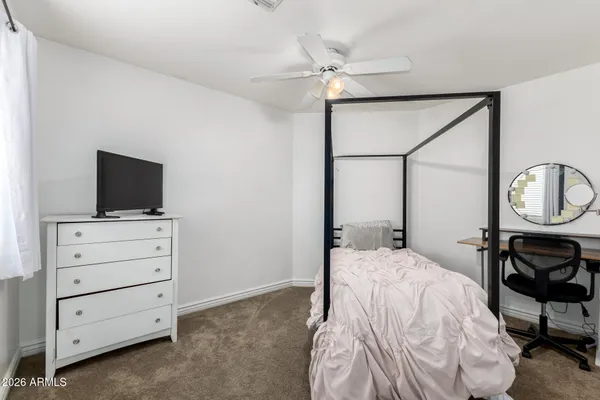 a bedroom with a bed a mirror on dresser and a flat screen tv