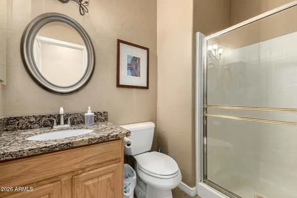 a bathroom with a granite countertop toilet a sink and a mirror