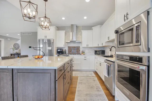 a kitchen with stainless steel appliances kitchen island granite countertop a sink a stove top oven a counter space and cabinets