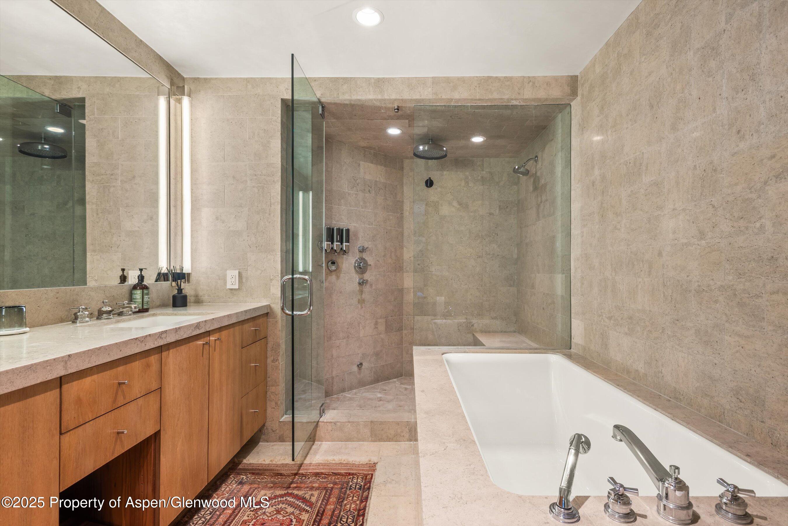 706 East Hyman Avenue, Unit 706 Aspen, CO 81611 - Photo 35 of 46 a bathroom with a granite countertop sink a mirror a bathtub and shower
