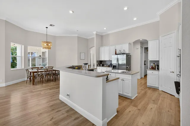 a living room with stainless steel appliances kitchen island a table and chairs in it