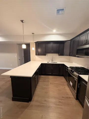 a large kitchen with stainless steel appliances kitchen island granite countertop a stove a sink dishwasher and a cabinets with wooden floor