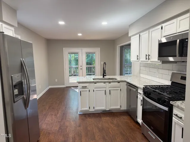 a kitchen with stainless steel appliances granite countertop a stove a sink and a refrigerator