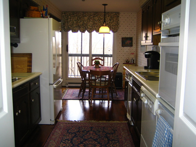 1140 Old Mill Road, Unit 504F Hinsdale, IL 60521 - Photo 11 of 21 a kitchen with stainless steel appliances granite countertop a stove a refrigerator a microwave a dining table and chairs with wooden floor