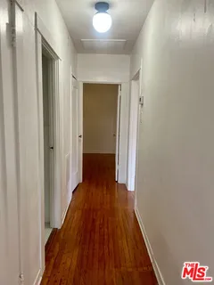 a view of a hallway with wooden floor and closet