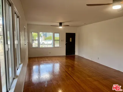 a view of an empty room with wooden floor and a window