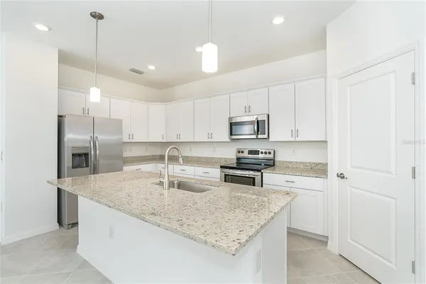 a kitchen with stainless steel appliances granite countertop a sink a stove and a refrigerator